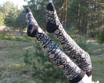 May include: A pair of black and white patterned knee-high socks with a geometric design. The socks are worn on a person's legs, with the feet pointing upwards.
