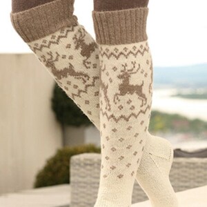 May include: A pair of white knee-high socks with a brown reindeer pattern. The socks have a brown cuff at the top.