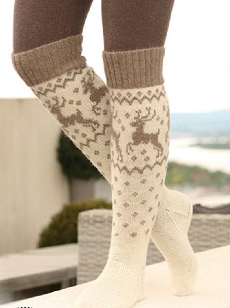 May include: A pair of white knee-high socks with a brown reindeer pattern. The socks have a brown cuff at the top.