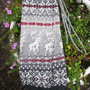 May include: Grey, white and red knitted leg warmers with a traditional Scandinavian pattern. The leg warmers have a long fringe.
