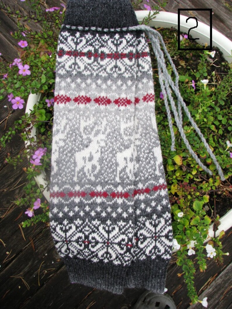May include: Grey, white and red knitted leg warmers with a traditional Scandinavian pattern. The leg warmers have a long fringe.