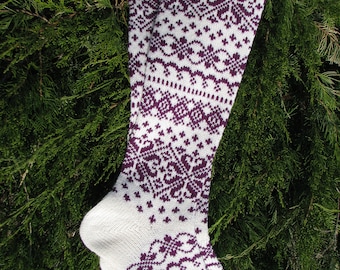 May include: A pair of white knee-high socks with a purple geometric pattern. The socks are knitted and have a ribbed cuff.