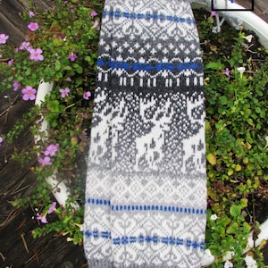 May include: Grey and white knitted leg warmers with a blue and white geometric pattern. The leg warmers have a white background with a grey and blue geometric pattern.