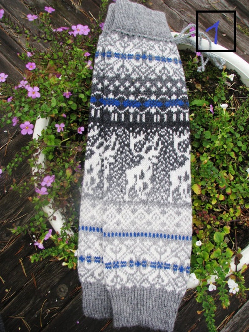 May include: Grey and white knitted leg warmers with a blue and white geometric pattern. The leg warmers have a white background with a grey and blue geometric pattern.