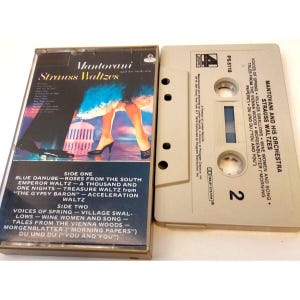 May include: A cassette tape with a beige case and a colorful cover featuring a couple dancing. The cover has the title "Mantovani Strauss Waltzes" and lists the songs on each side. The cassette tape is labeled "PS-5118" and has the number "2" on the side.