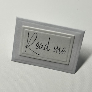 Puede incluir: Tarjeta blanca con un borde en relieve y el texto "Read me" en escritura negra.
