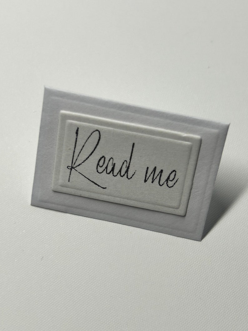 Puede incluir: Tarjeta blanca con un borde en relieve y el texto "Read me" en escritura negra.
