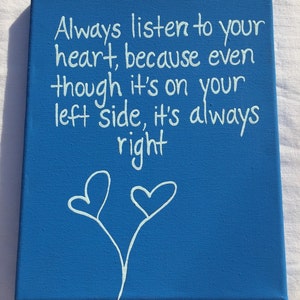 May include: Blue canvas with white text that reads "Always listen to your heart, because even though it's on your left side, it's always right". Two white hearts are drawn at the bottom of the canvas.
