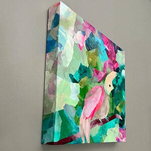 May include: Abstract painting of a pink bird with a white head perched on a branch in a colorful, leafy forest. The painting is done in a collage style with different shades of green, blue, pink, and purple.