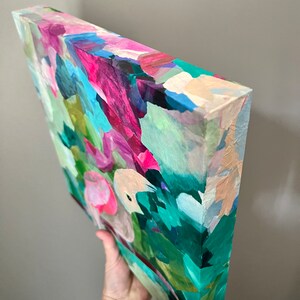 May include: Abstract painting on canvas with a textured surface. The painting features a variety of colors, including pink, green, blue, and white. The colors are blended together in a loose and gestural style, creating a sense of movement and energy.