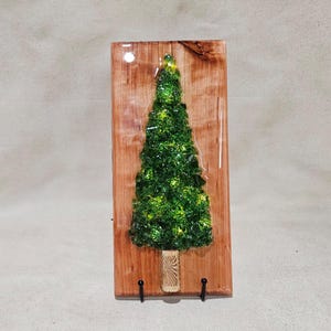 砕いた緑色のガラスで飾られたクリスマスツリーのオーナメント。樹脂で覆われた杉板に飾られ、冬のホームデコレーションに光沢のある松の木を模しています。