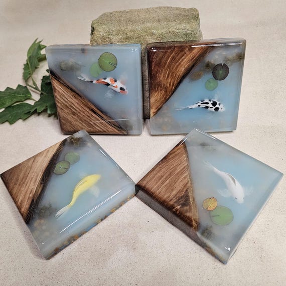 Walnut and resin poured into a koi pond motif — functional coasters that double as tiny zen art pieces on your desk.