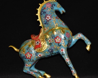 May include: A turquoise horse figurine with floral patterns in red, white, and purple. The horse has gold accents on its mane, hooves, and saddle. The figurine is posed with one leg raised, giving it a dynamic appearance. The figurine is likely made of metal.