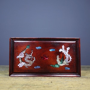 May include: A rectangular wooden tray with a dark red finish. The tray features a decorative design of a dragon and a phoenix, both made of iridescent mother-of-pearl inlay. The design is set against a background of clouds and flames.