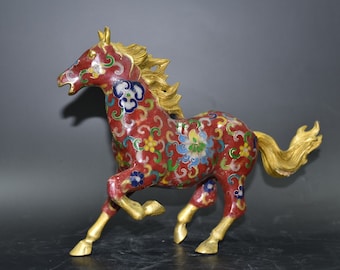 May include: A red, gold and blue cloisonné horse figurine. The horse is running and has a flowing mane and tail. The figurine is decorated with intricate floral patterns.