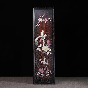 May include: A rectangular wooden panel with a dark brown finish, featuring an inlaid design of two birds perched on a branch with flowers. The flowers are in shades of pink, white, and yellow, creating a decorative artwork.