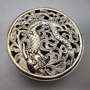 Pode incluir: Queimador de incenso de prata com um design detalhado de um dragão e padrões florais. O queimador é redondo e tem um design delicado e intrincado.