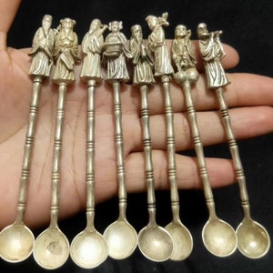 Può includere: Set di dieci cucchiaini d'argento con piccole figure di uomini cinesi sui manici. I cucchiaini hanno un design a forma di bambù sui manici.