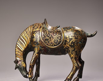 May include: Bronze horse sculpture with a saddle, featuring intricate gold-coloured floral patterns. The horse is in a grazing pose, with its head lowered. The sculpture has a weathered, antique appearance.