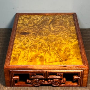 May include: A wooden stand with intricate carvings and a smooth, golden-brown top. The stand is made of dark wood with a rich, natural finish.