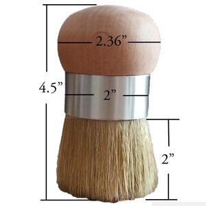 May include: A round wooden handled brush with a silver metal band and light tan bristles. The brush has a total height of 4.5 inches, a handle diameter of 2.36 inches, a metal band width of 2 inches, and a bristle length of 2 inches.