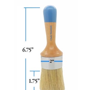 May include: A round paint brush with a light wood handle, a blue painted top, and natural bristles. The brush features a silver metal ferrule and the text Chalk Mountain on the handle. Dimensions are 6.75 inches total length, 2 inches wide, and 1.75 inches for the bristles.