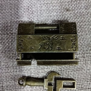May include: Antique-style brass lock with a key. The lock has an ornate design with a dragon motif and a keyhole. The key is also made of brass and has a simple design.