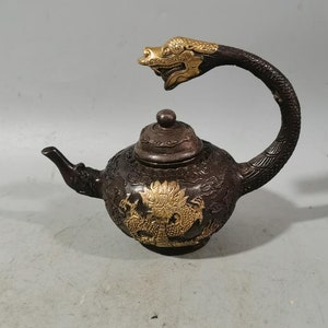 May include: A dark brown teapot with a dragon-shaped handle and lid. The teapot is decorated with gold-coloured dragons and other designs.