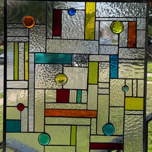 May include: A stained glass window with a geometric design featuring various colours, including red, orange, yellow, green, blue, and white.