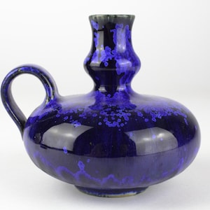 Könnte beinhalten: Eine blaue Keramikvase mit breiter Basis und schmalem Hals. Die Vase hat eine gefleckte Glasur mit einem dunkelblauen Grund und hellblauen Sprenkeln.