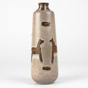 Puede incluir: Un jarrón alto de cerámica marrón claro con un diseño estilizado de dos caballos en esmalte marrón. El jarrón tiene un fondo redondeado y un cuello estrecho.