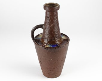 May include: A brown ceramic vase with a wide base and a narrow neck. The vase has a handle and a blue and yellow glaze around the top.