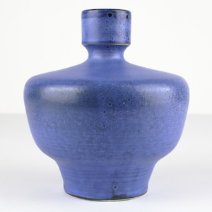 Può includere: Un vaso in ceramica blu con una superficie testurizzata e una base larga e arrotondata. Il vaso ha un collo stretto e un'apertura leggermente svasata.