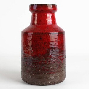 May include: A red ceramic vase with a brown glaze. The vase has a rounded body and a narrow neck.