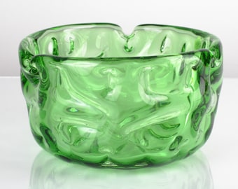 May include: A green glass bowl with a textured, wavy surface. The bowl is round and has a wide opening.