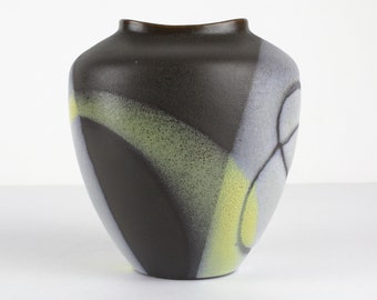 May include: A dark brown ceramic vase with abstract geometric designs in shades of green, yellow, and white.