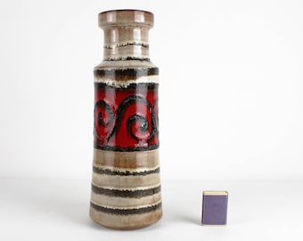 May include: A tall, ceramic vase with a brown, white, and red glaze. The vase has a swirling pattern in red and black on the middle section. The vase is approximately 30 cm tall.