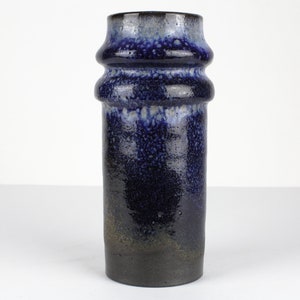 Könnte beinhalten: Eine blaue und weiße Keramikvase mit einer strukturierten, gesprenkelten Glasur. Die Vase hat eine zylindrische Form mit drei erhabenen Bändern um die Mitte.