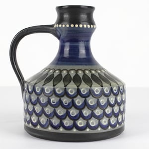 Peut inclure: Un vase en céramique bleu et blanc avec une anse. Le vase présente un motif géométrique d'écailles et de feuilles.