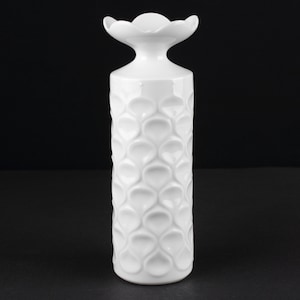 Puede incluir: Jarrón de cerámica blanco con un patrón único en forma de corazón y una parte superior decorativa.