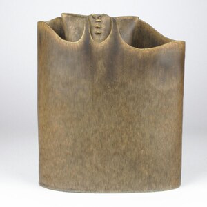 May include: A brown ceramic vase with a unique, folded design. The vase has a textured surface and a slightly rounded shape.