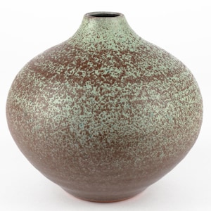 Può includere: Un vaso in ceramica verde e marrone macchiettato con corpo arrotondato e collo stretto.