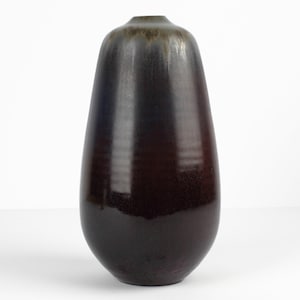 Könnte beinhalten: Eine hohe, dunkelbraune Keramikvase mit glänzender Oberfläche. Die Vase hat eine abgerundete, tropfenförmige Form und einen subtilen Farbverlauf von Dunkelbraun zu Hellbraun an der Oberseite.
