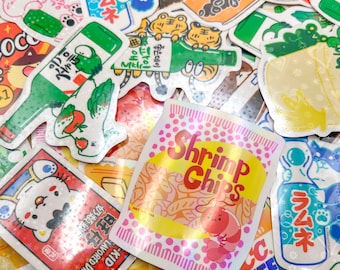 以下が含まれることがあります： 様々なデザインのカラフルなステッカーのコレクション。漫画の動物、食べ物、飲み物などがあります。ステッカーはホログラフィックで、光沢のある仕上げになっています。一部のステッカーには日本語が書かれており、「ラムネ」と「좋은데이」が含まれています。