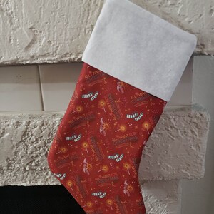 May include: Red Christmas stocking with a white cuff. The stocking is decorated with a repeating pattern of stars, wands, and the text "All I Want For Christmas".