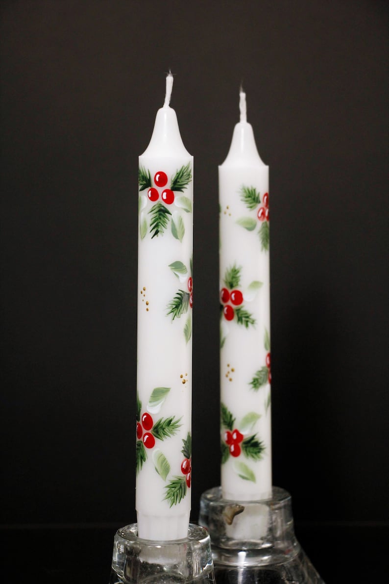 seven inch taper white taper candles hand painted with a design of red holly berries and leaves every quarter turn on a diagonal . perfect for a Christmas celebration. also available in ten, and 14 inch candles