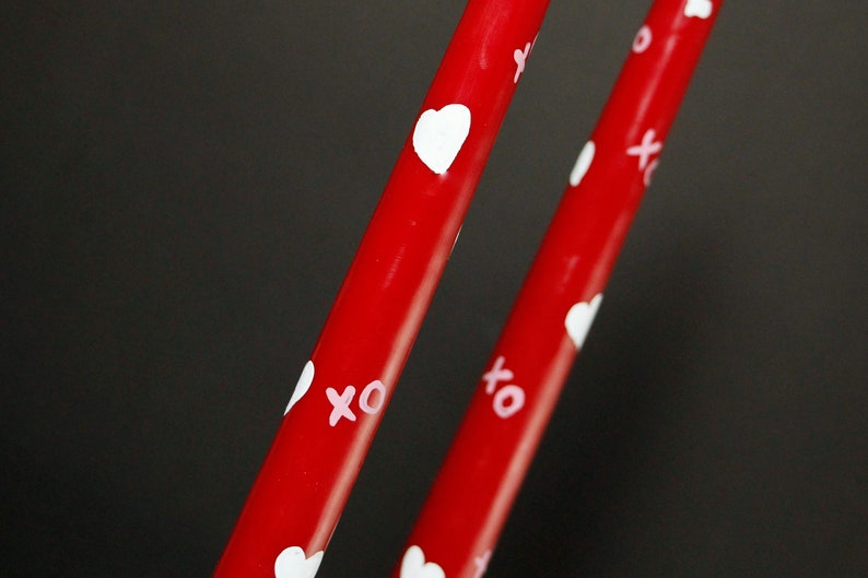 Red taper candles with painted white hearts and pink x's and o's (hugs and kisses)