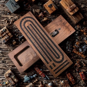 May include: A wooden cribbage board with black inlay and the text "The Murphy's" engraved on the lid. The board is open, revealing the peg storage. Assorted wooden game pieces and decorative blocks are scattered around the board.