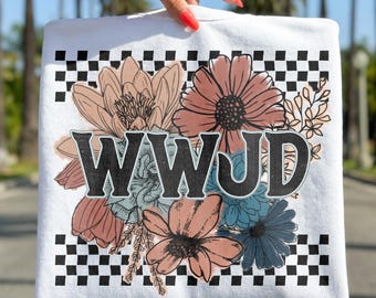 May include: White sweatshirt with a floral design and the letters WWJD in black. The flowers are in shades of peach, blue, and pink. The top and bottom edges have a black and white checkered pattern.