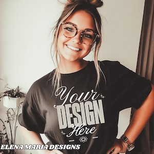 May include: A woman wearing a black t-shirt with the text "Your Design Here" in white. The shirt is a mockup for a design project.